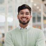 Happy, confident and portrait of Indian man in office with creative professional at tech startup. Ambition, smile and face of businessman with pride, growth and opportunity in future business market.